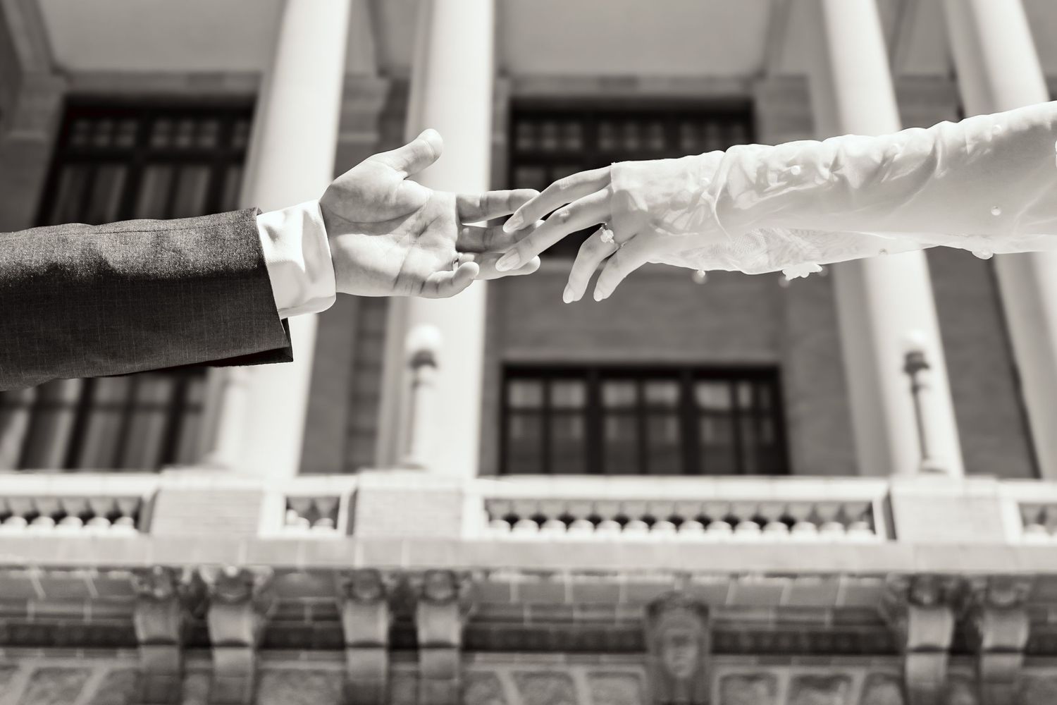 Delicate hands of the bride and groom in front of the 1910 Harris County Courthouse in Houston, Texas.