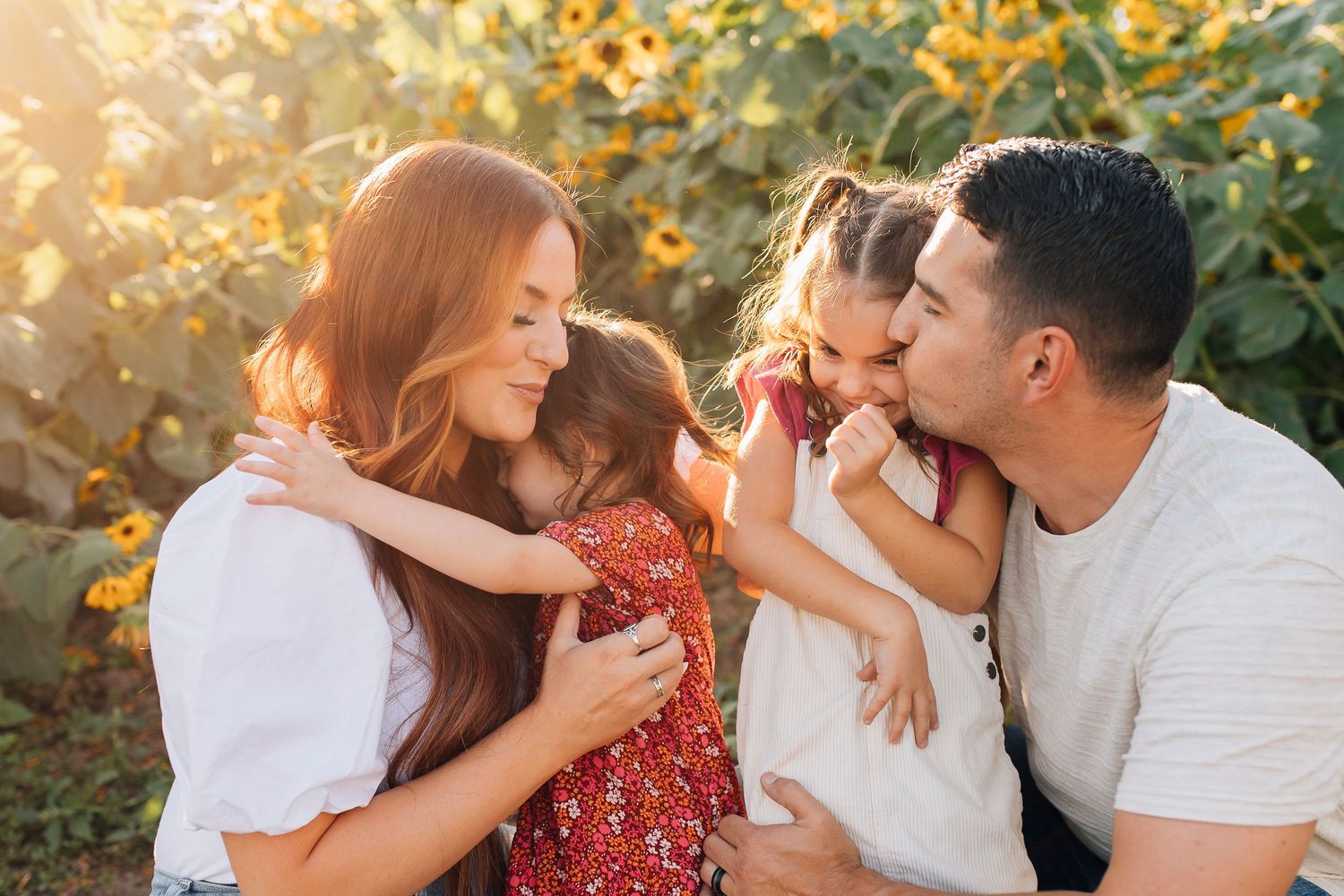 A family shares a tender moment together outdoors at sunset with golden foliage in the background.