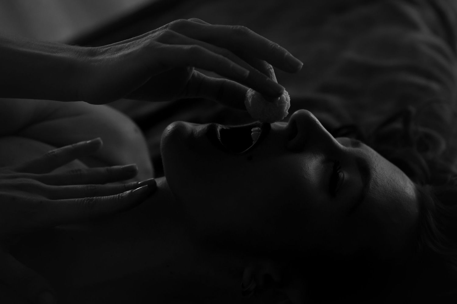 Artistic close-up photograph with dramatic shadows and gentle hand gesture.