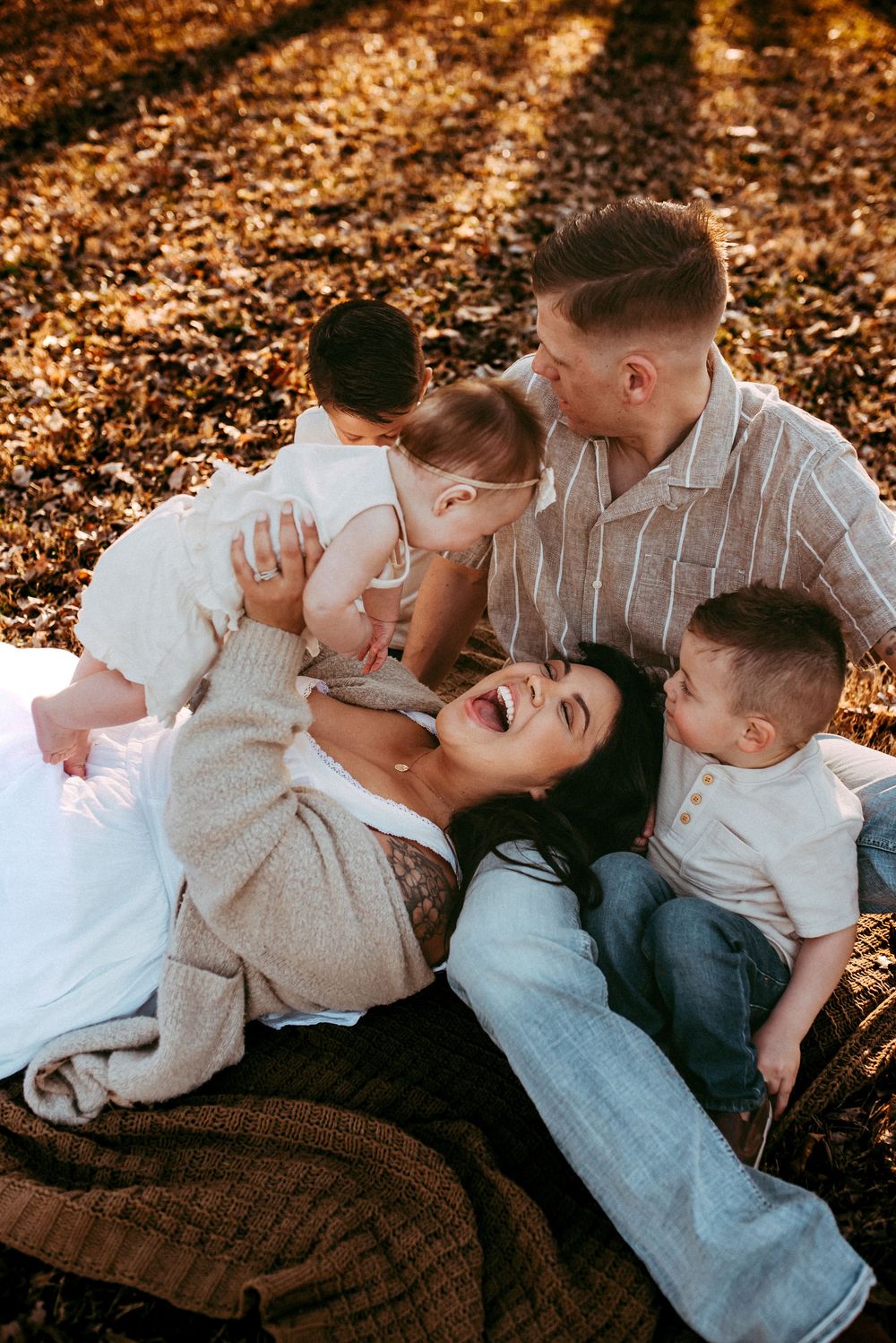 Family of 5 cuddling on the floor as mom holds the baby in the air and laughs in Clarksville, Tennessee.
