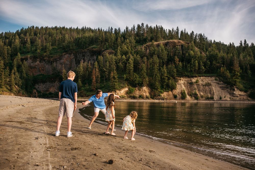 Family skipping rocks at the lake in Spokane, Washington.