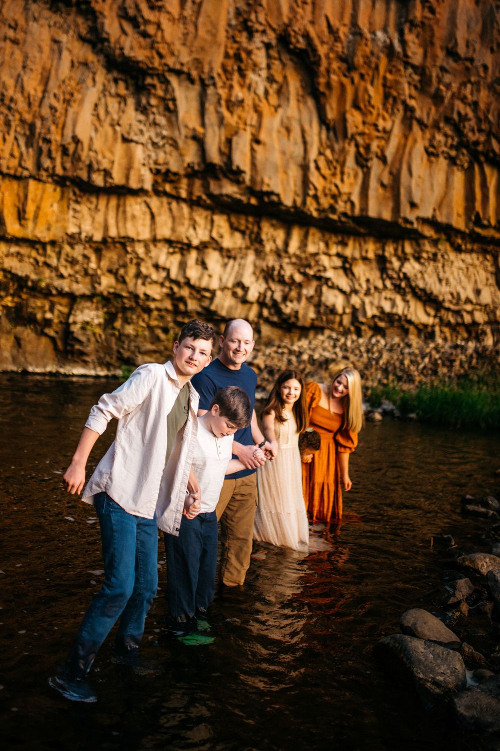 Family playing in the waterfall at sunset in Spokane, Washington.