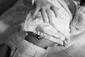 Close-up black and white shot of fresh diaper being fastened on baby in changing position.