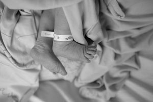 Black and white series of close-up photos showing gentle hands cradling and caring for a newborn baby.
