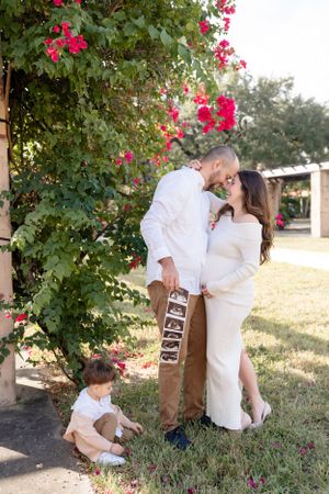 Family poses together near blooming pink bougainvillea in an outdoor garden setting.