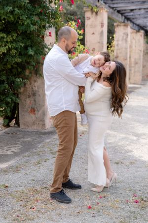 Romantic couple in white and tan clothing share an intimate moment in a garden setting.