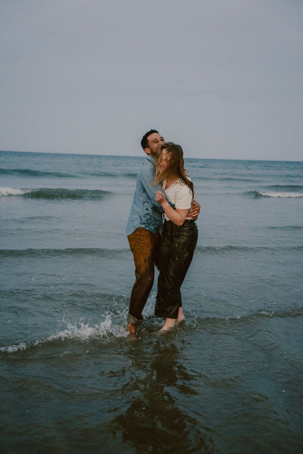Couple sharing an intimate moment while standing in ocean waves.