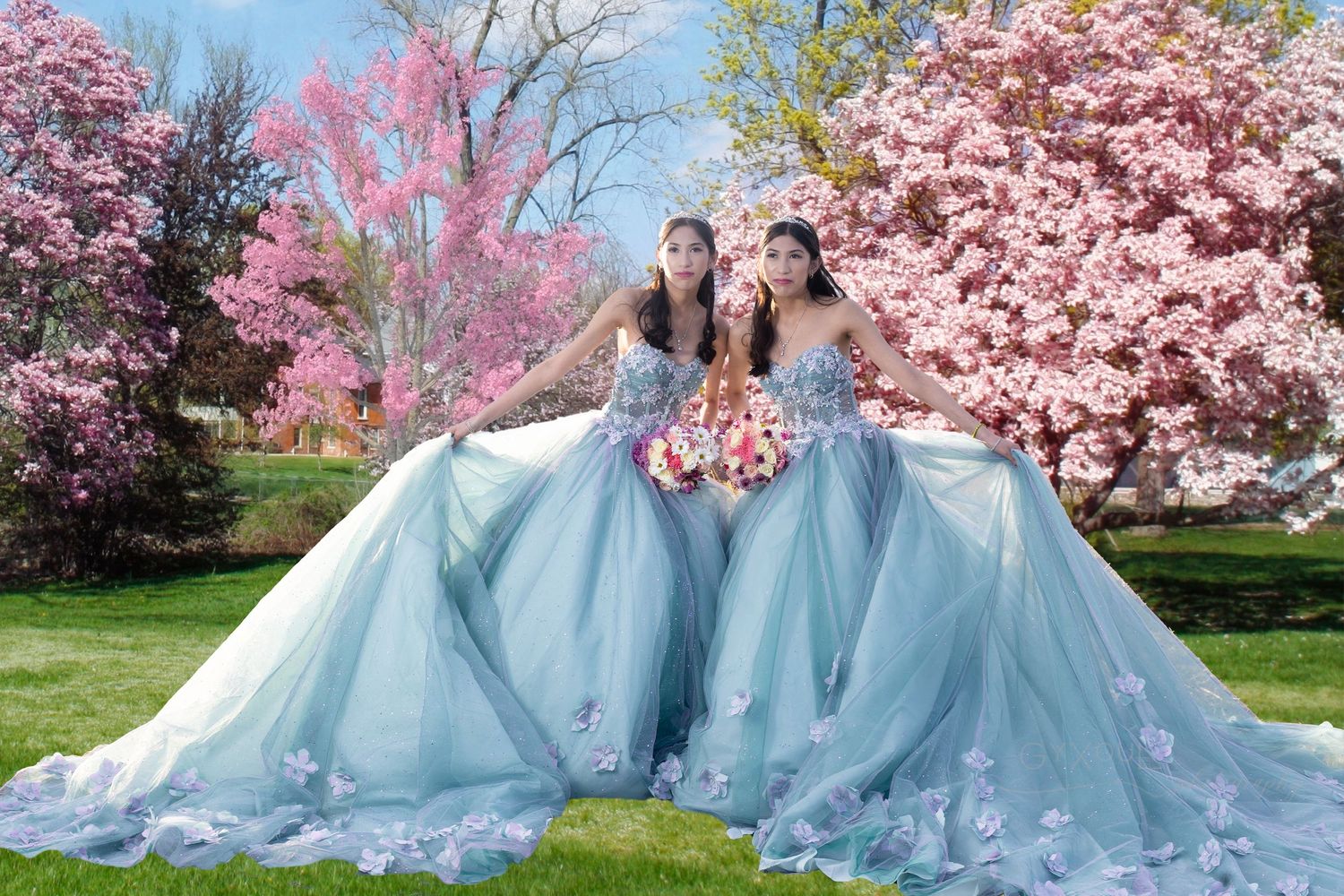 Two people wearing matching blue ballgowns posing under blooming cherry blossom trees.