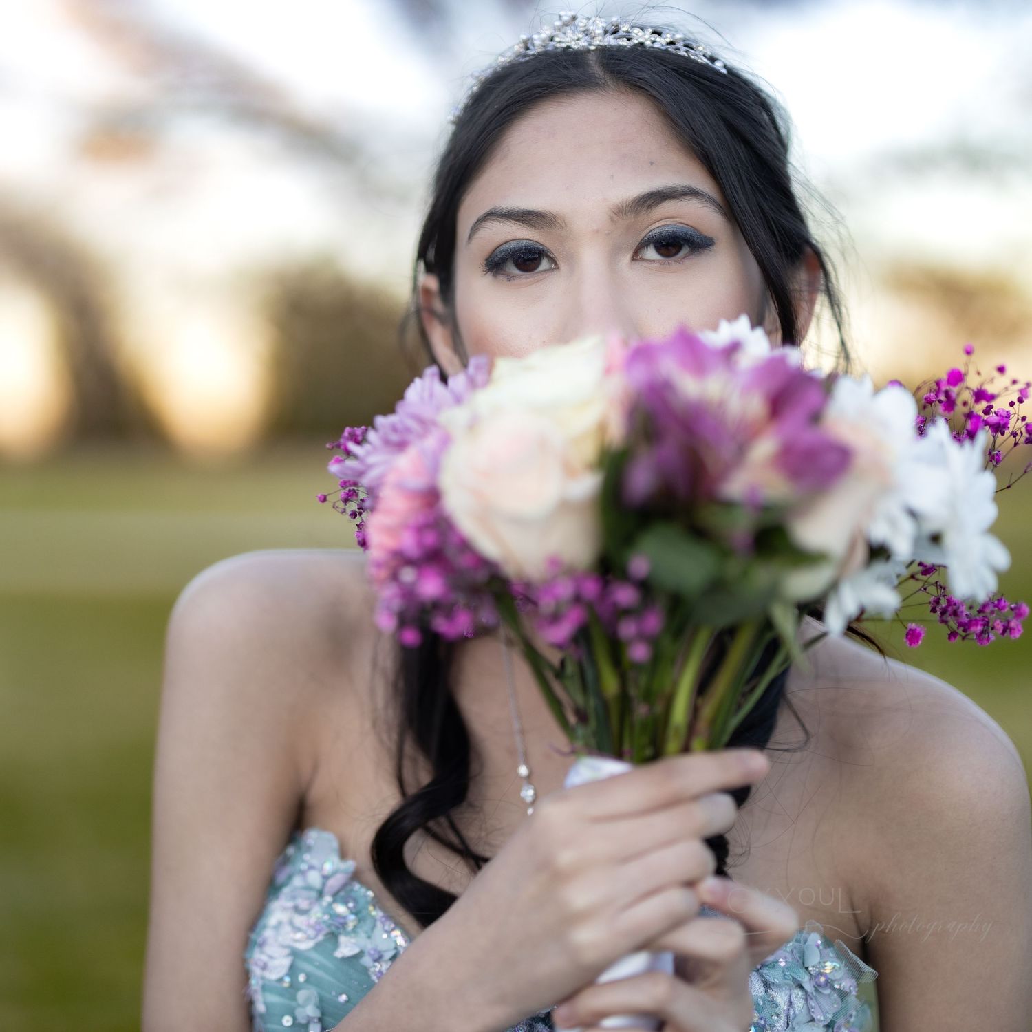 Elegant portrait with mixed floral bouquet and sparkly blue gown with tiara.