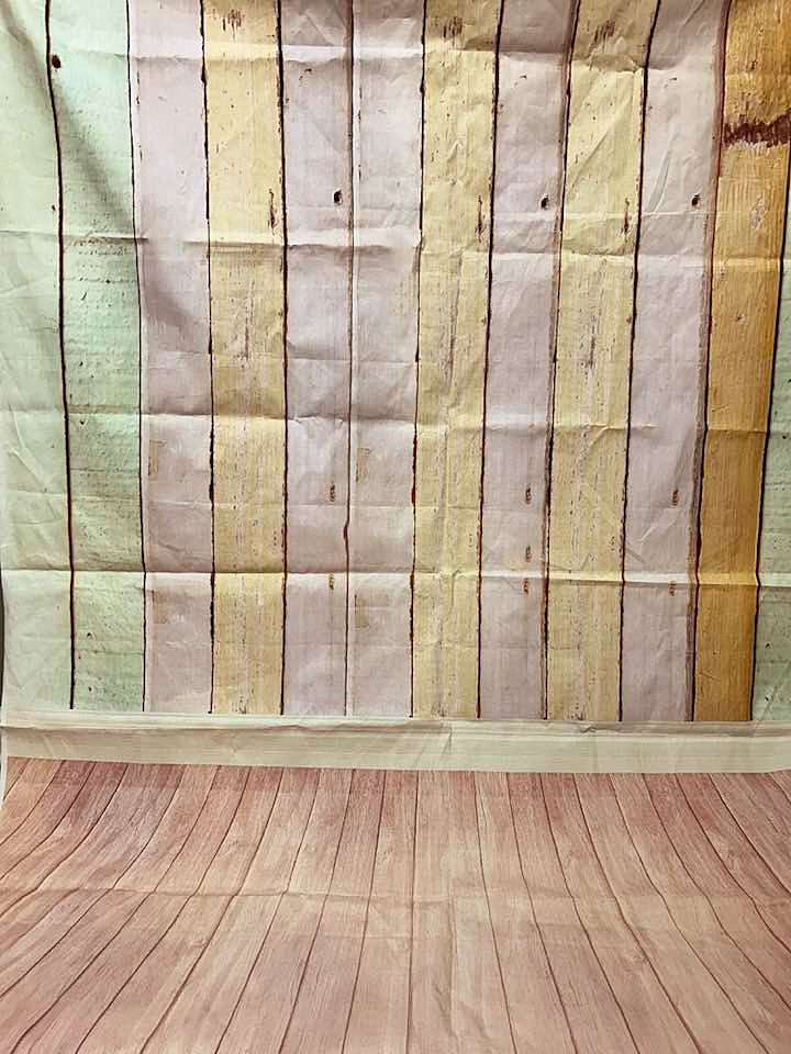 Empty vintage photography studio backdrop with pastel striped walls and wooden floor.