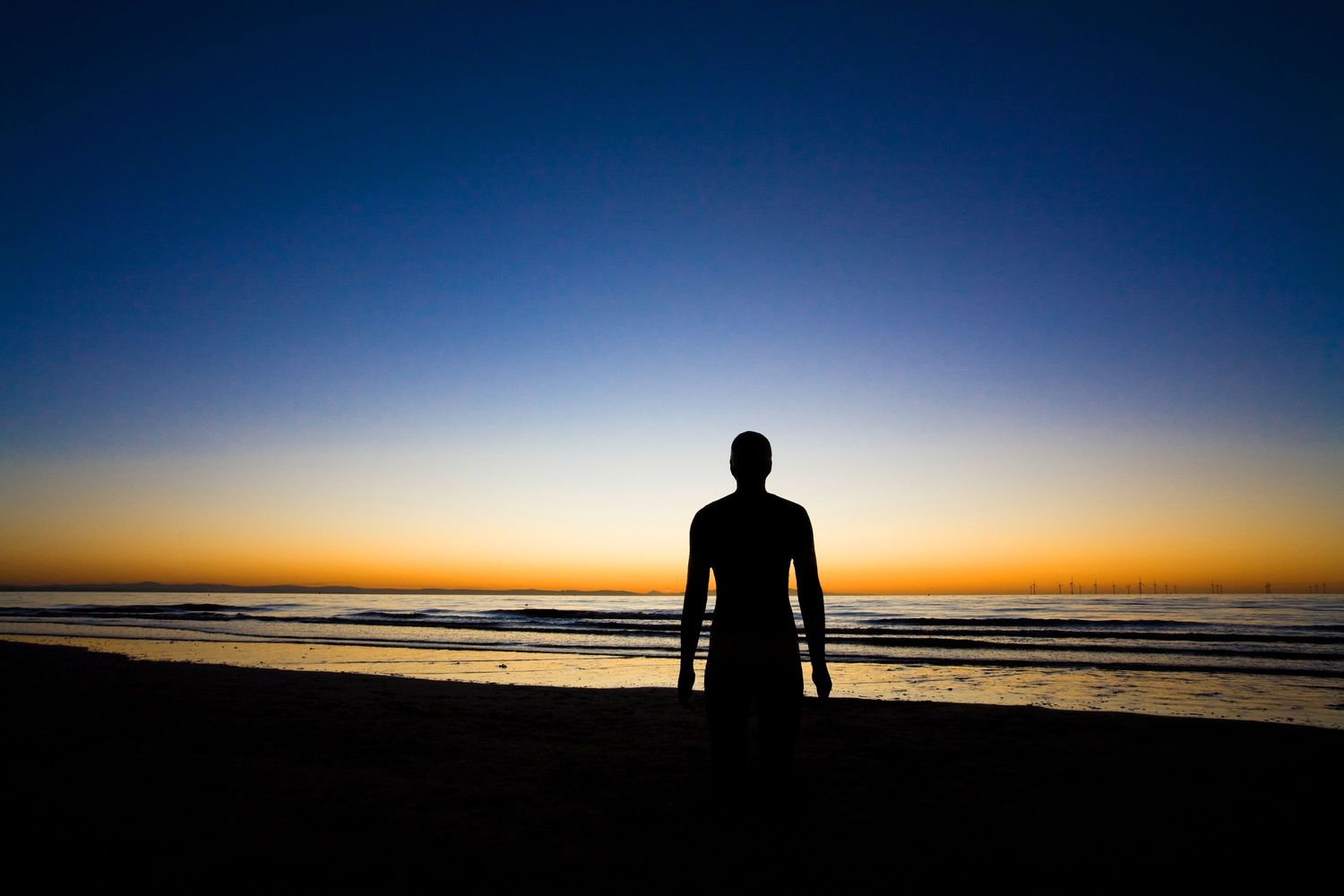 Anthony Gormley's Iron Men installation at Sunset, Crosby, Merseyside, United Kingdom.