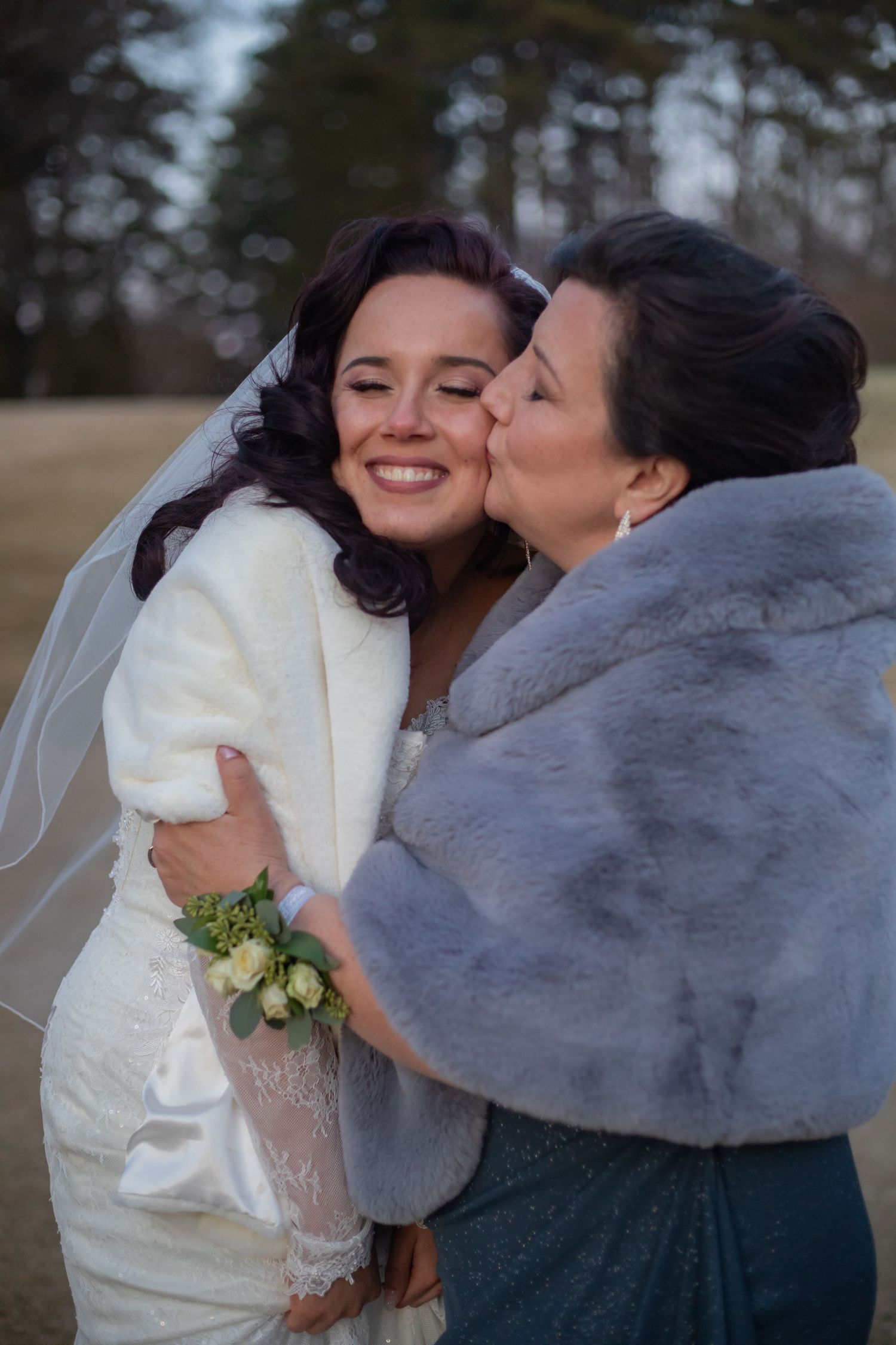 A tender moment between two people in winter coats during a wedding celebration.