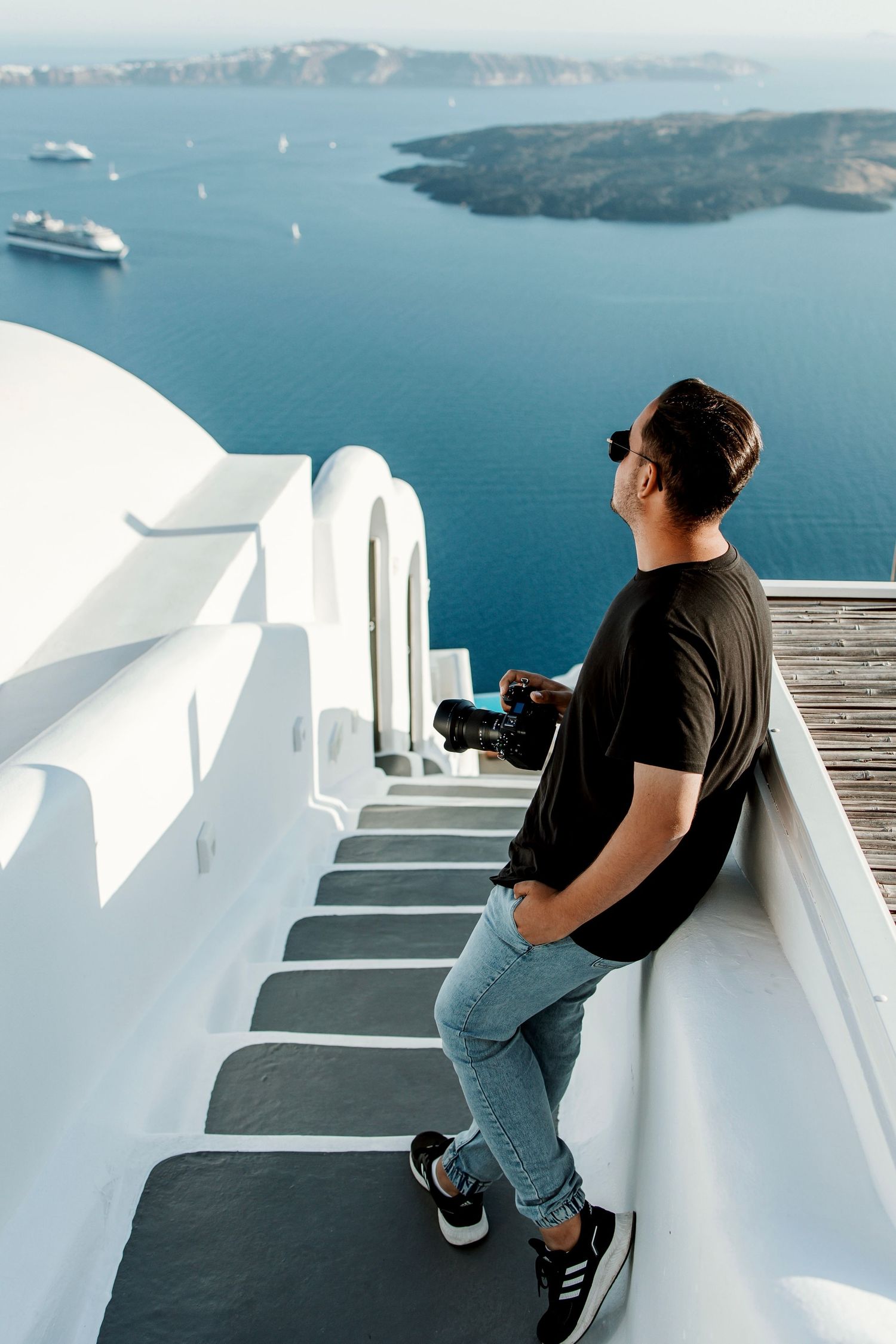 Photographer standing on white steps overlooking Mediterranean sea and cruise ships.