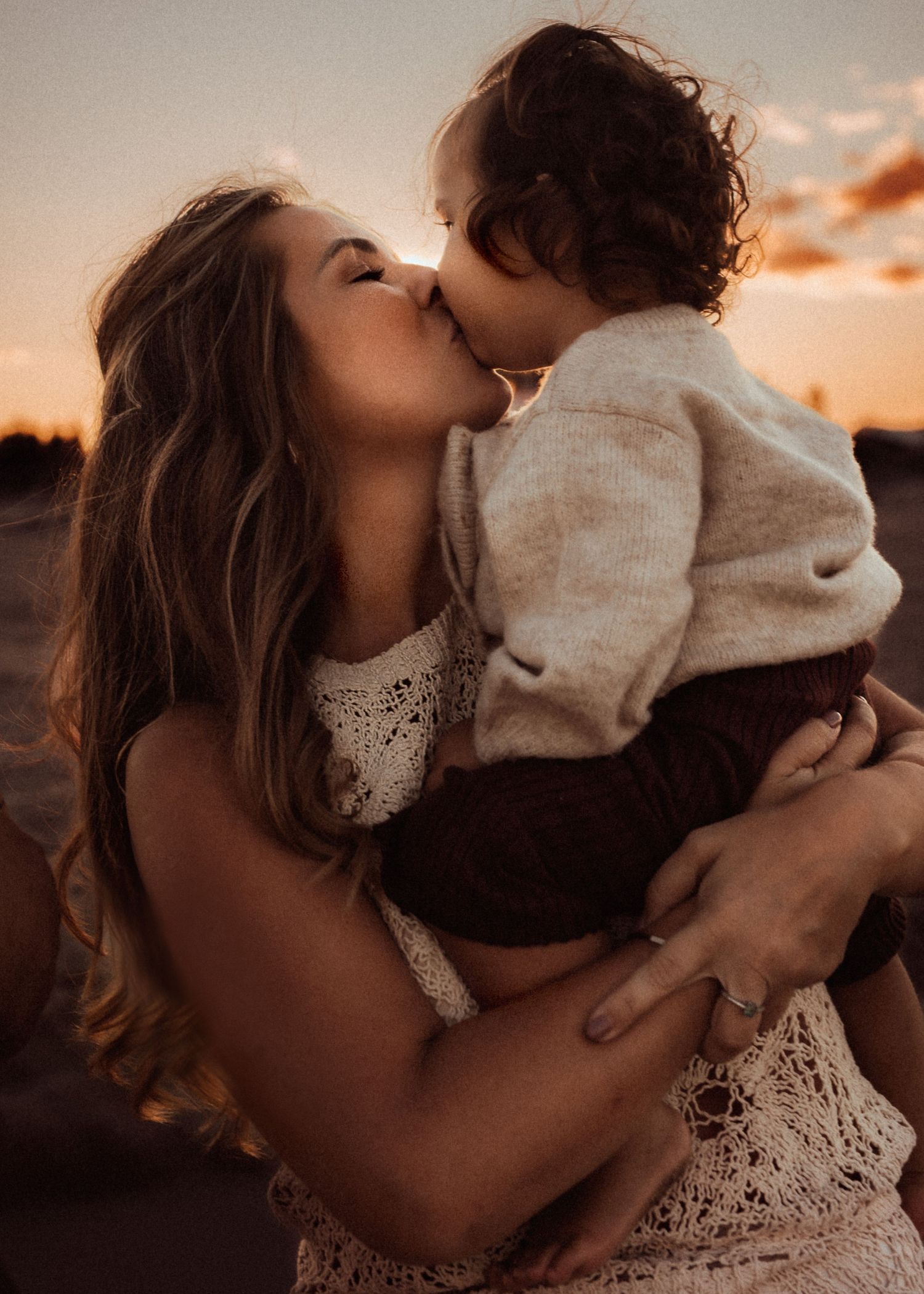 A tender moment between mom and child in Denia  silhouetted against a warm sunset sky. Denia family photographer