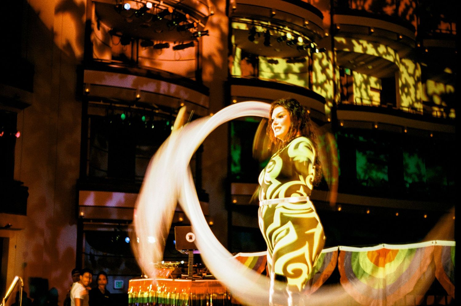A glowing crescent moon decoration illuminates a storefront display with yellow and green lighting at night.