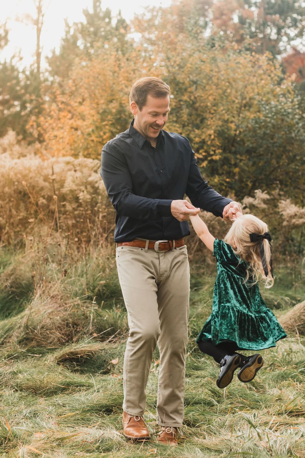 Father playing with daughter during lifestyle family photo session in Heritage Park, Farmington Hills, Michigan. tSouth Lyon, Michigan