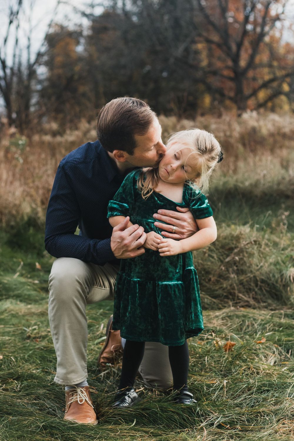 Father giving his daughter a kiss on the cheek during a lifestyle family photography session in Farmington Hills, Michigan.