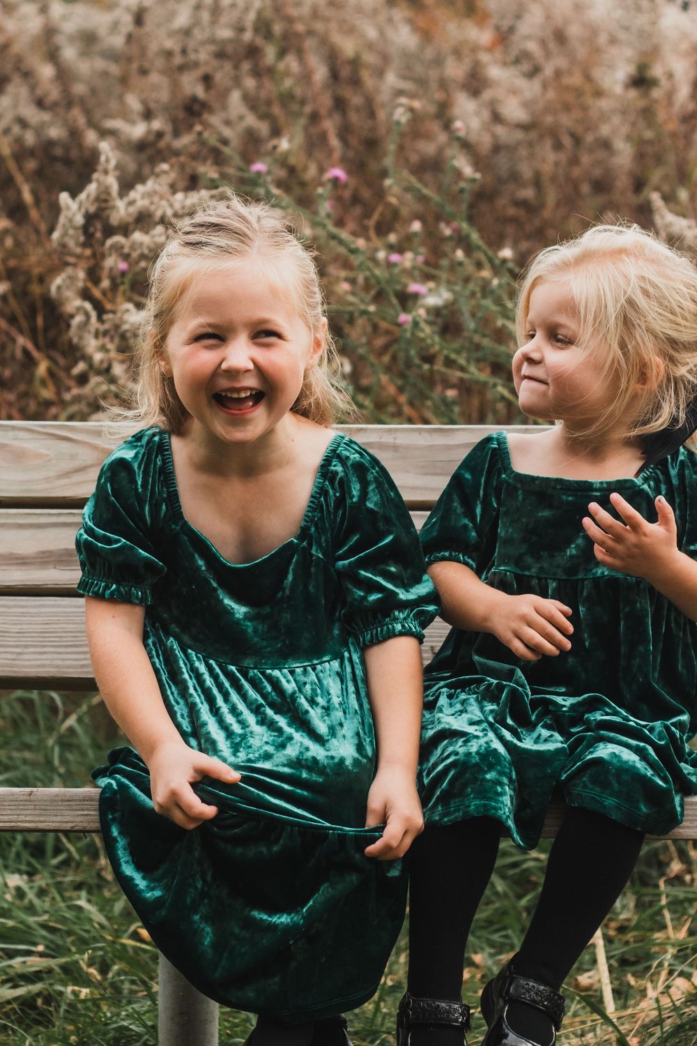 Two little girls smiling and being silly during a golden hour lifestyle family photography session in Farmington Hills, Michigan.