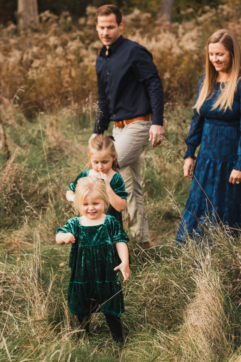 Family walking through long grass during a golden hour lifestyle family photography session in Farmington Hills, Michigan.