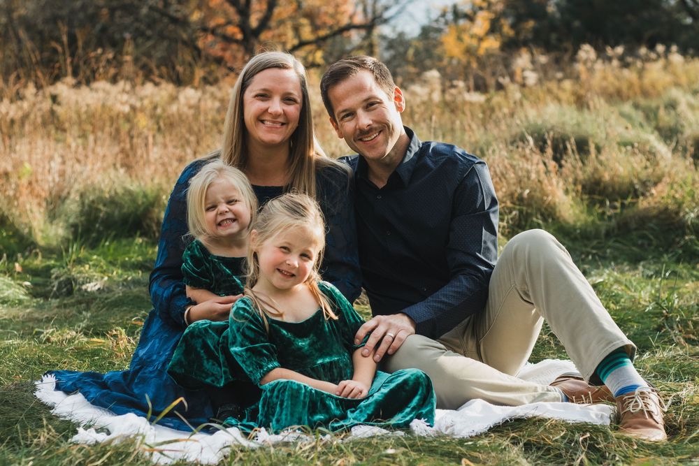 Family sitting together on a blanket smiling during a lifestyle family photography session in Farmington Hills, Michigan.