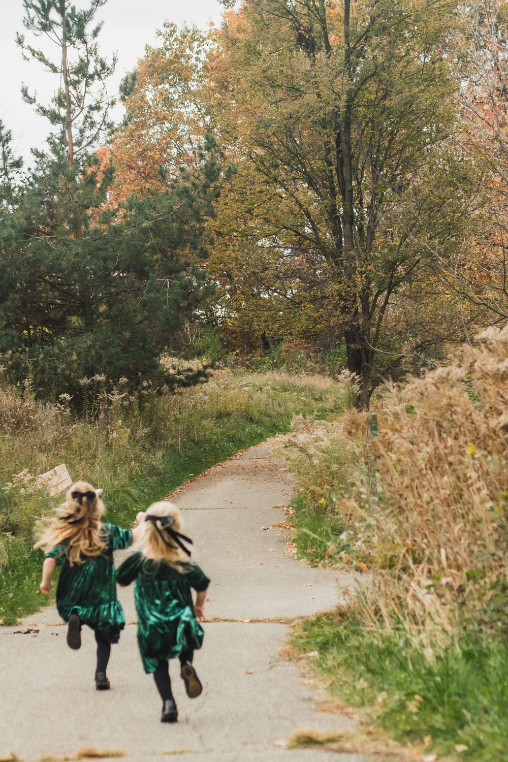 Two little girls running down a trail during a lifestyle family photography session in Farmington Hills, Michigan.