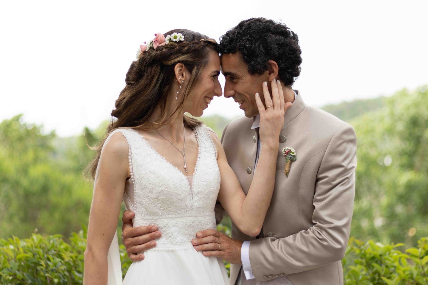 An intimate wedding portrait of newlyweds sharing a tender moment in a garden setting.