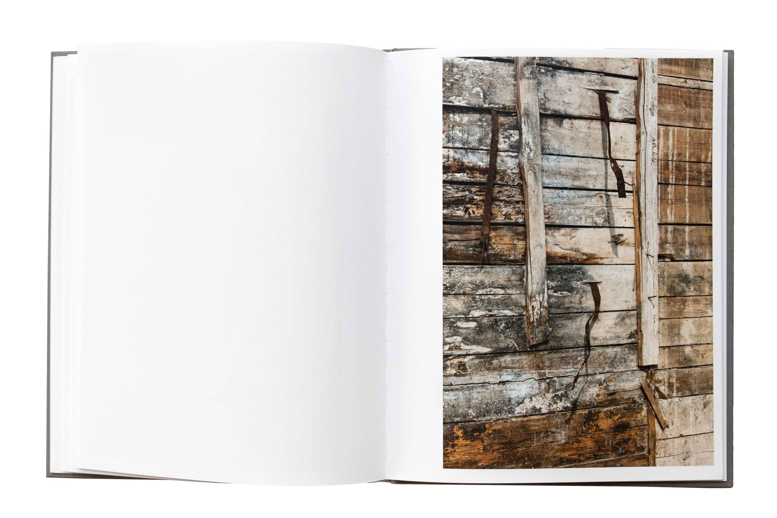 Open art book displaying architectural photographs with stone walls and textured surfaces.