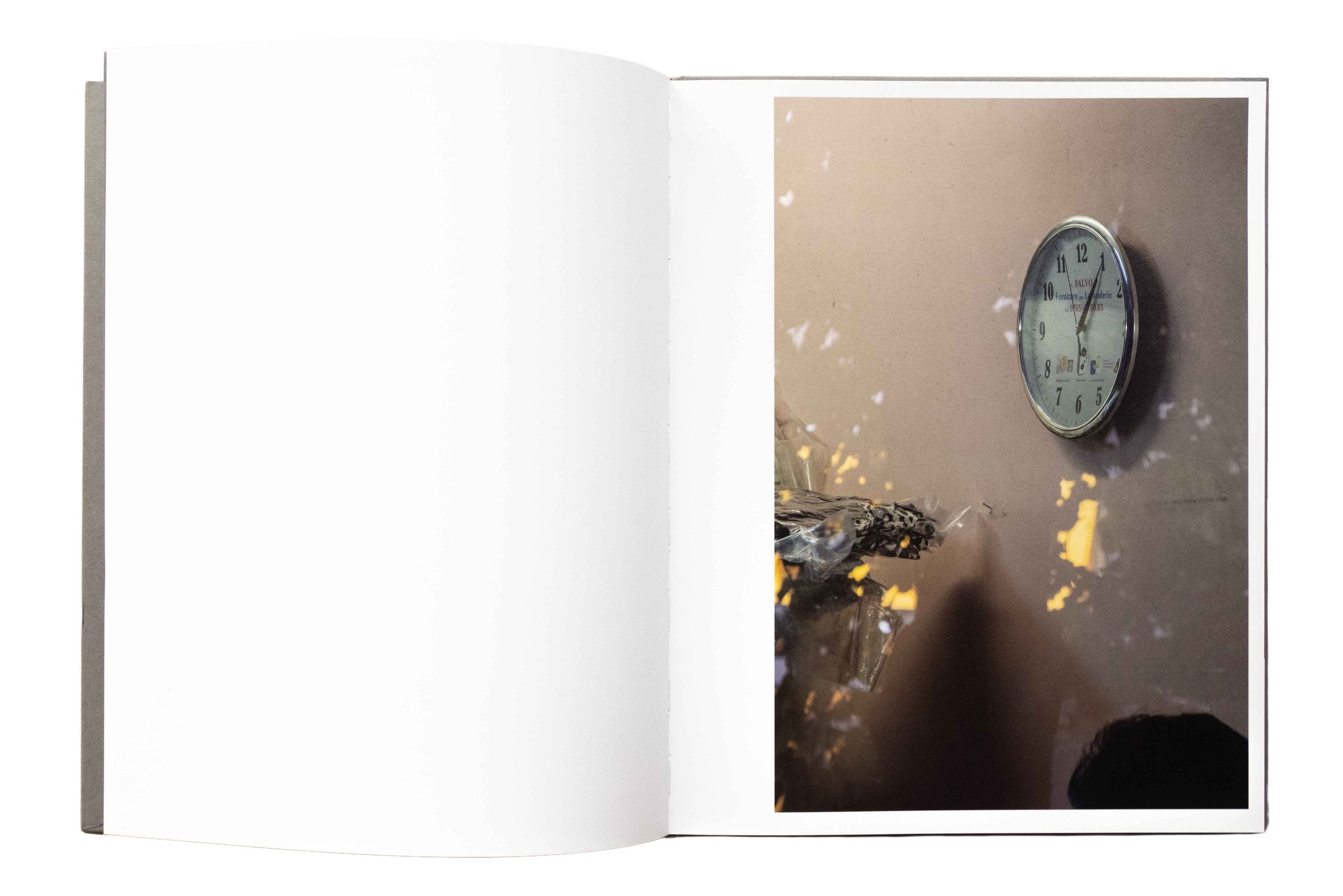 An open book displays a photograph of a vintage wall clock and abstract elements.