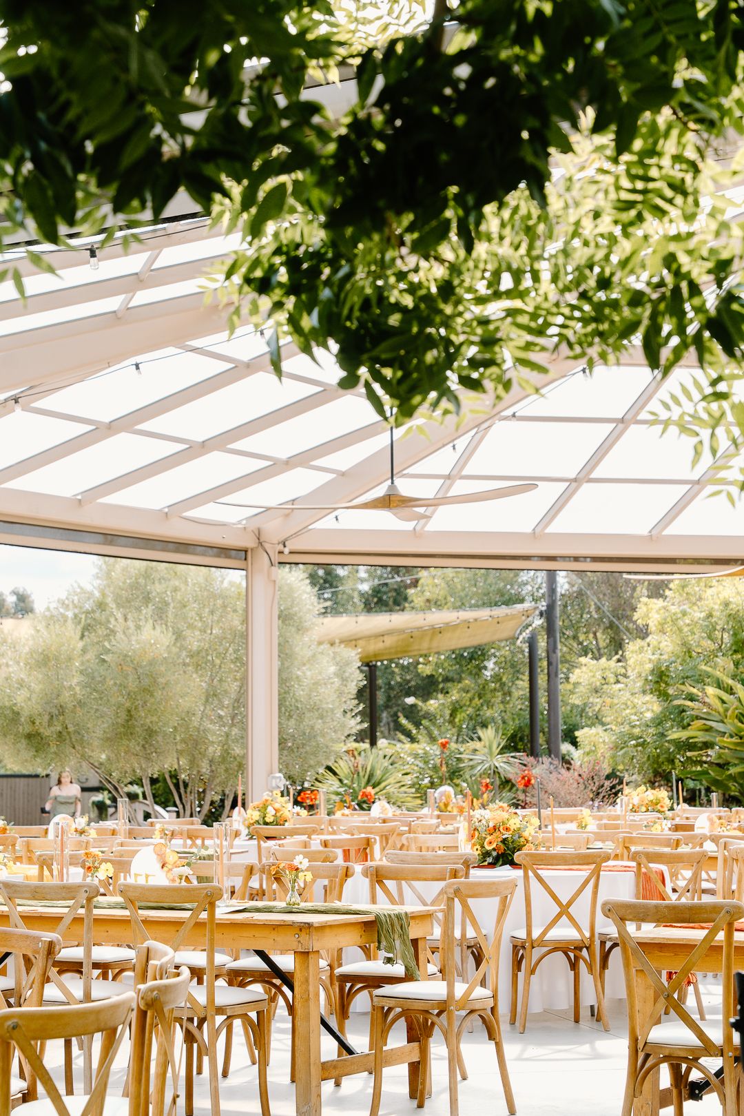 A couple shares a romantic moment under a white parasol among blooming pink azalea bushes on their wedding day.