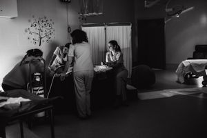 Black and white wide shot of a medical procedure room with equipment and staff.