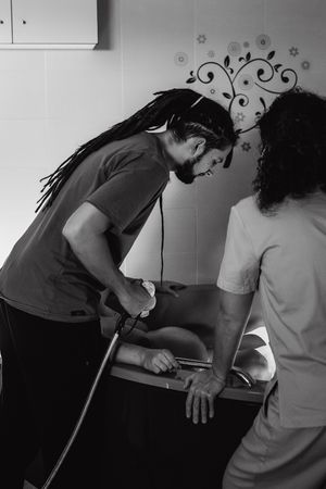 Medical professionals work together during a clinical procedure in black and white.