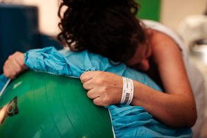 Healthcare providers assist during a medical procedure with patient in blue hospital gown.