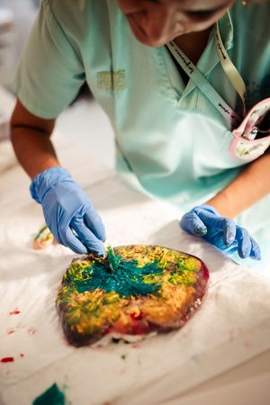 Medical professional in scrubs examining colorful dyed placental tissue.