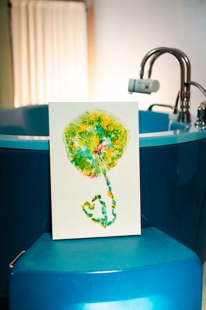 Artistic prints of placental blood vessels in vibrant green and yellow displayed on blue surface.
