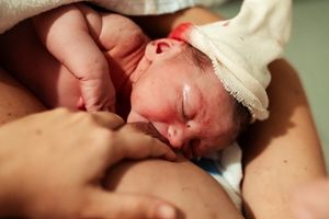 Tender newborn care moment captured in soft natural lighting.