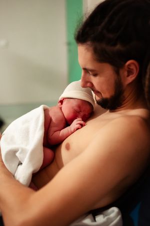 Close-up of nurturing skin-to-skin contact in soft green lighting.