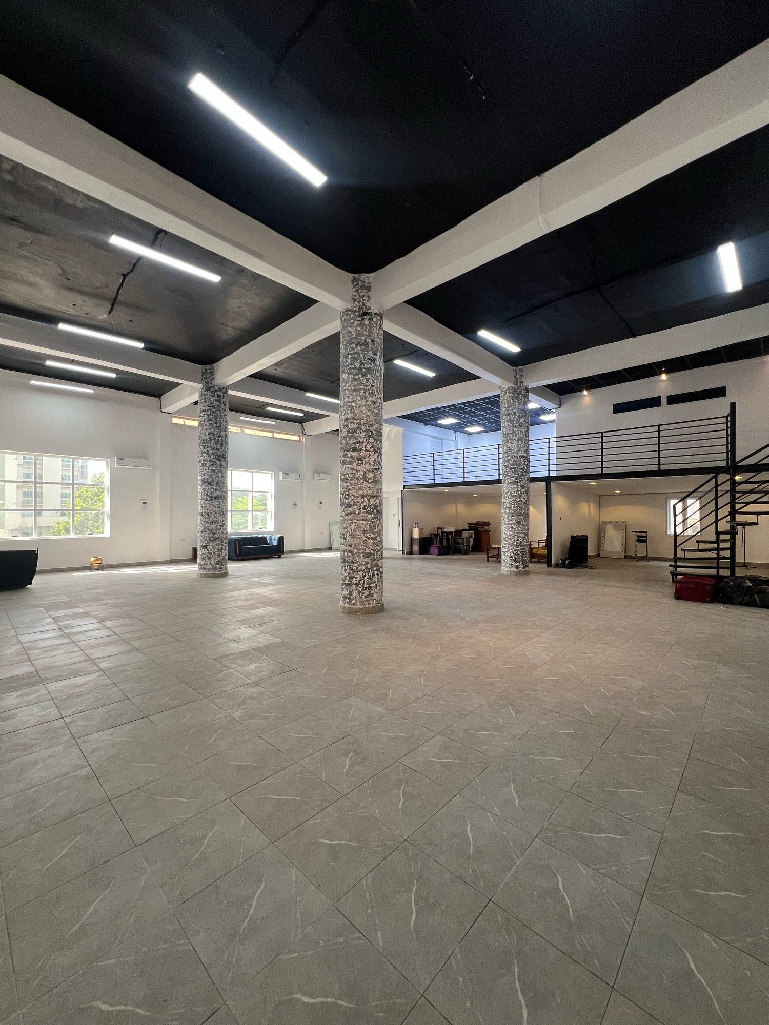 Modern industrial open space with concrete pillars, black ceiling and fluorescent lighting. - Affinity Arts Studio