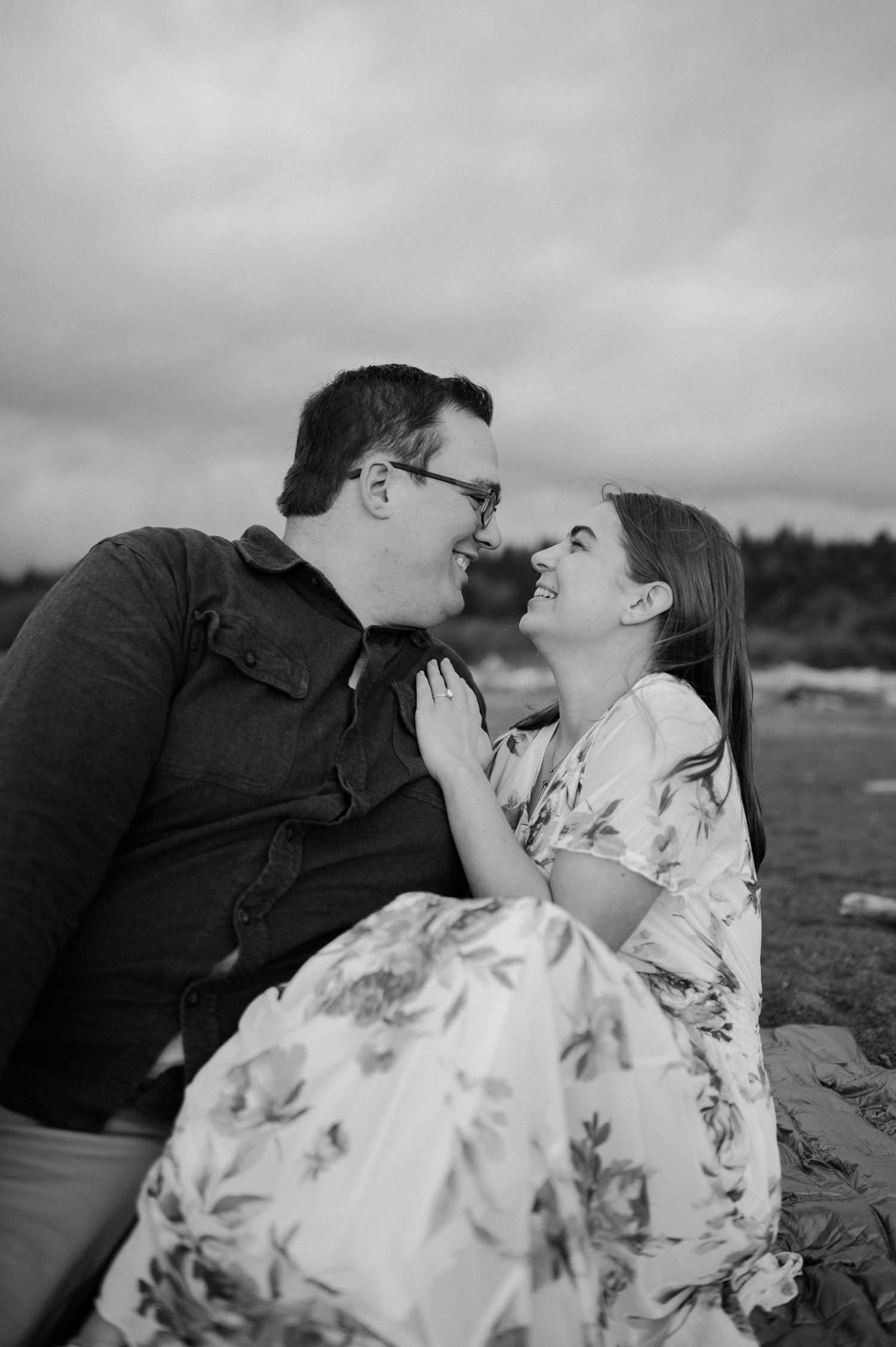 An intimate black and white portrait of a couple sharing a romantic moment on the beach.