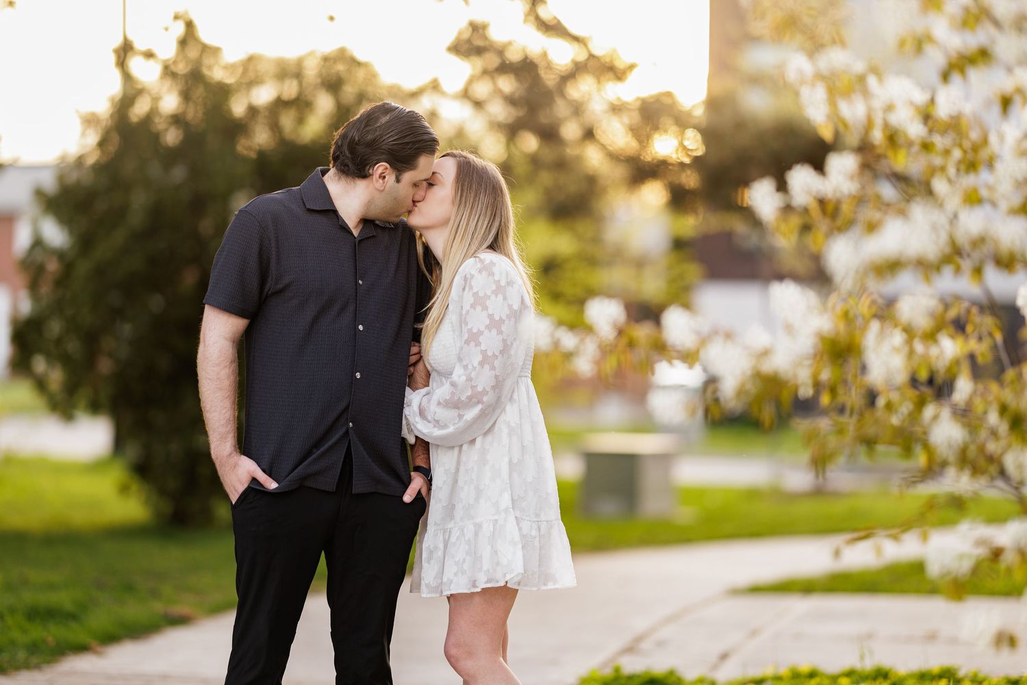 Couple in black and white outfits share tender moments at sunset in a lush outdoor garden setting.