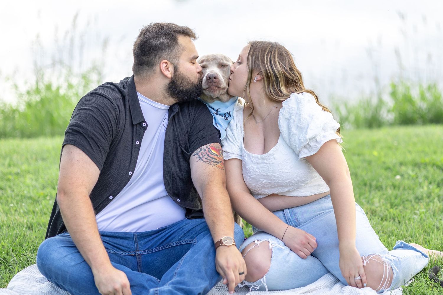 Springfield, IL photographer captures an expecting couple kissing their dog during a session in Central, IL
