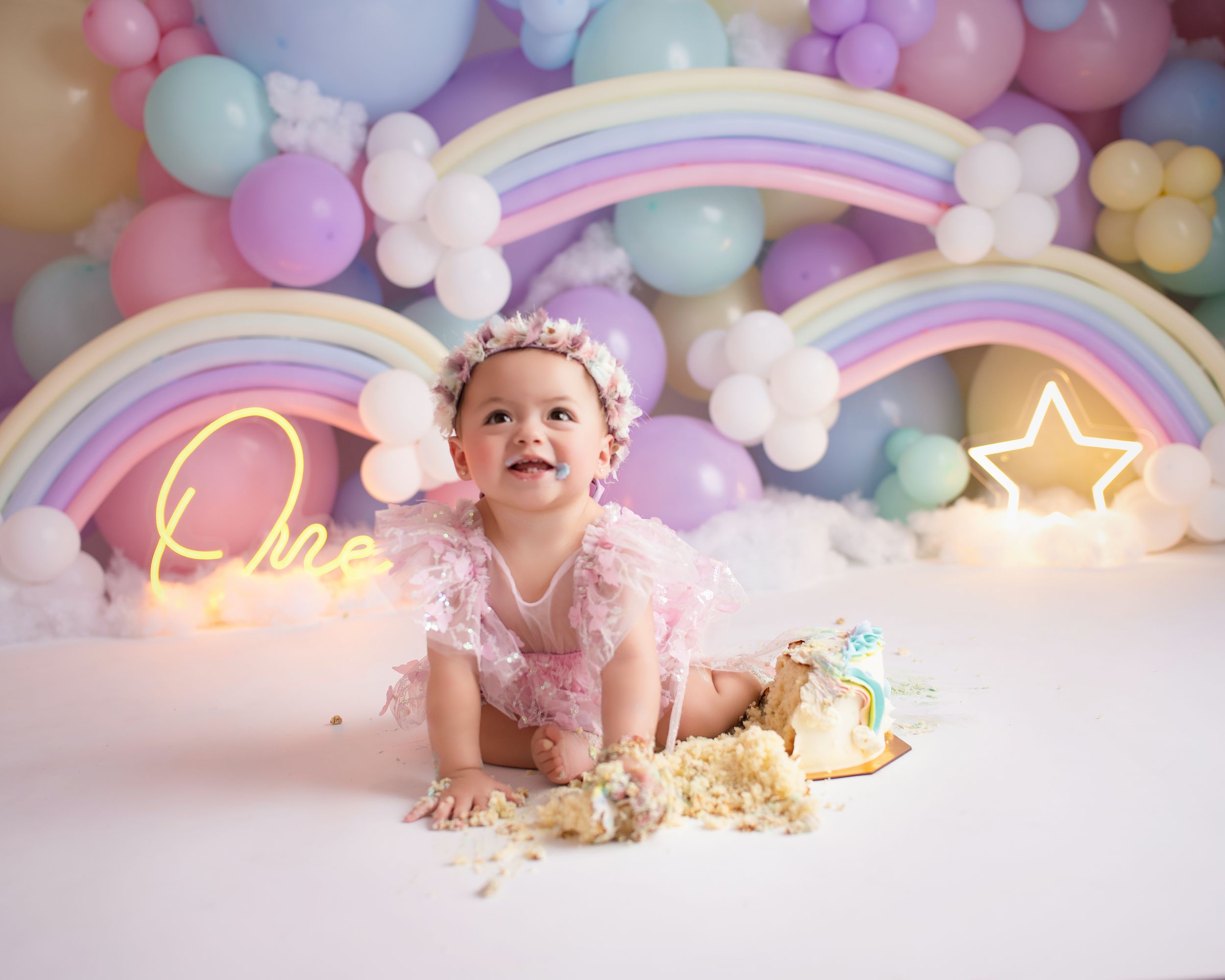Festive cake smash photography setup with neon lights and scattered cake pieces.