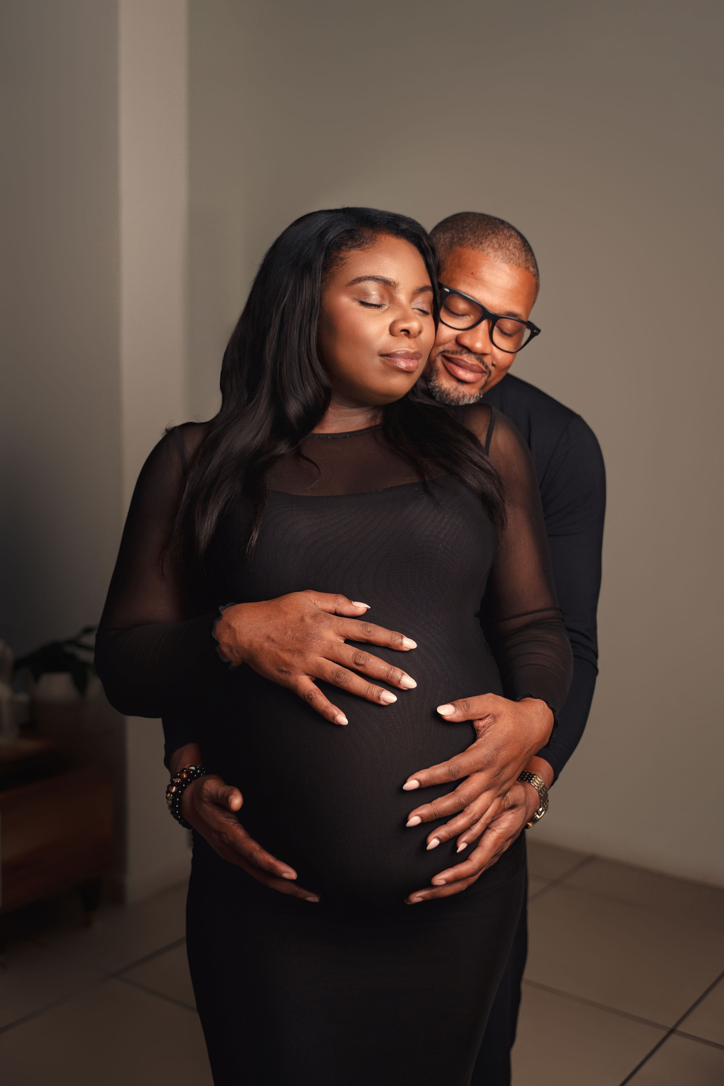 A tender maternity photo series shows a couple embracing the pregnant belly in a studio setting.
