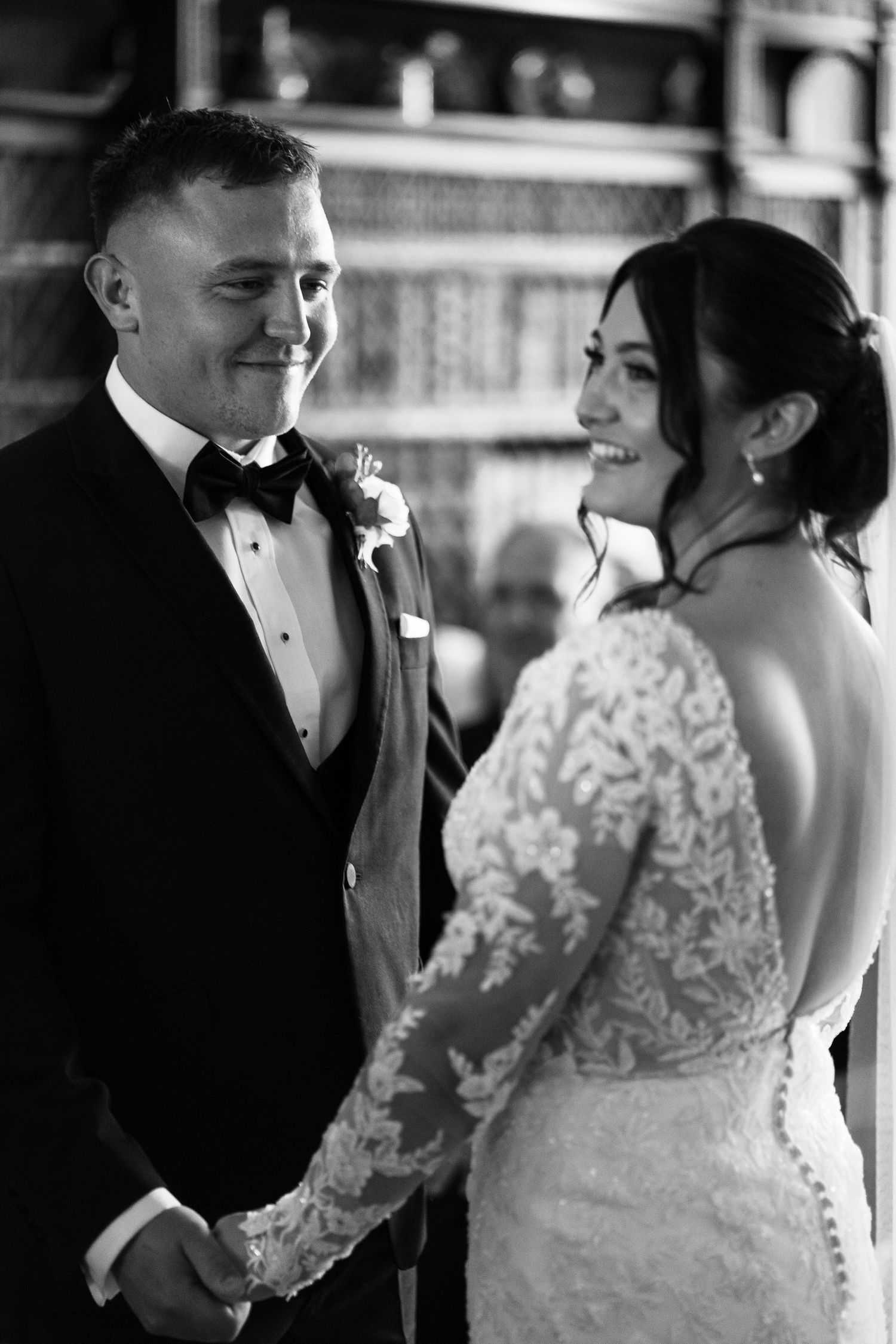 Bride and groom lovingly smile at each other, embraced behind greenery with a spring-summer glow in The Park, Nottingham city elopement.