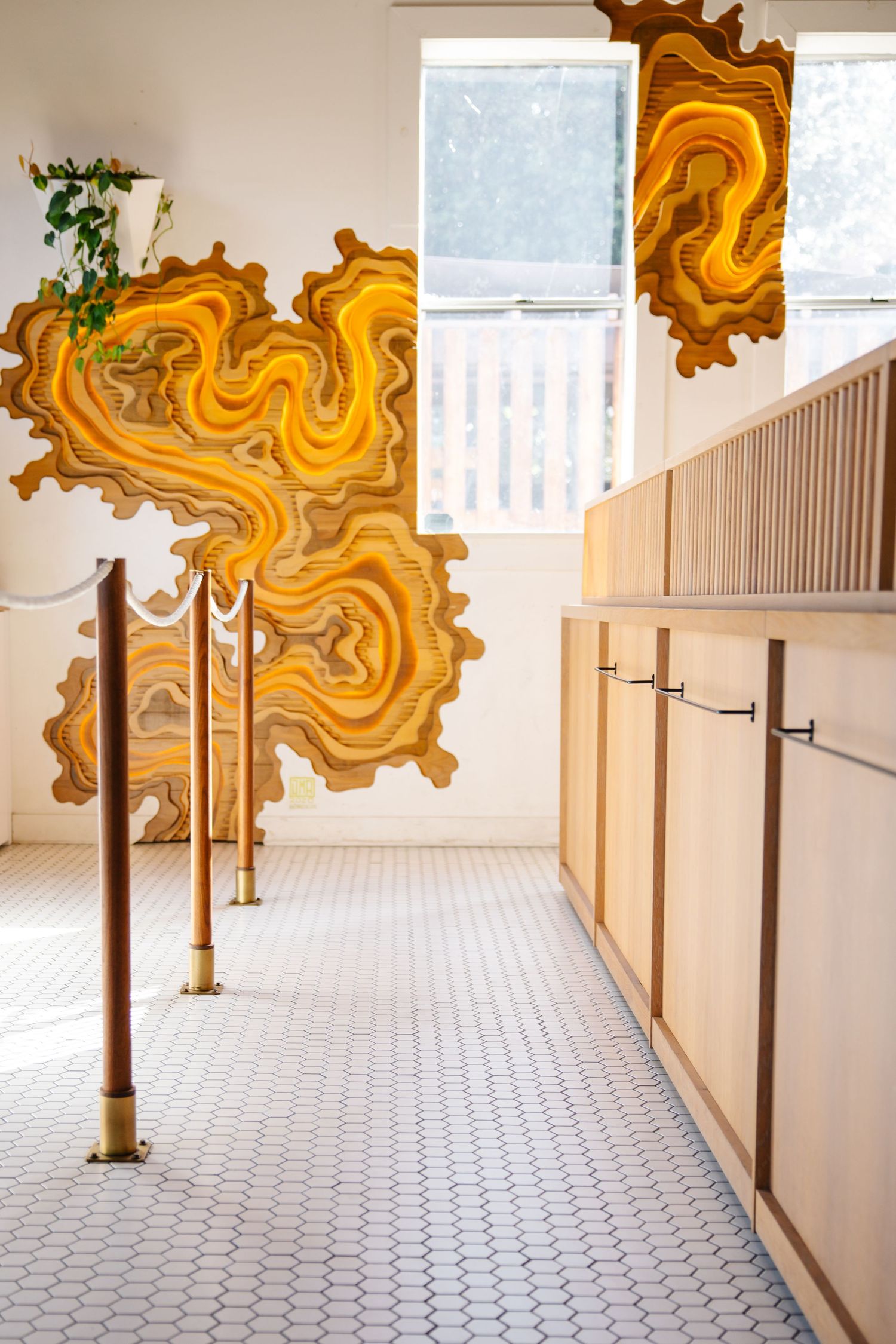 Modern hallway with striking orange geometric wall art and white tile flooring.