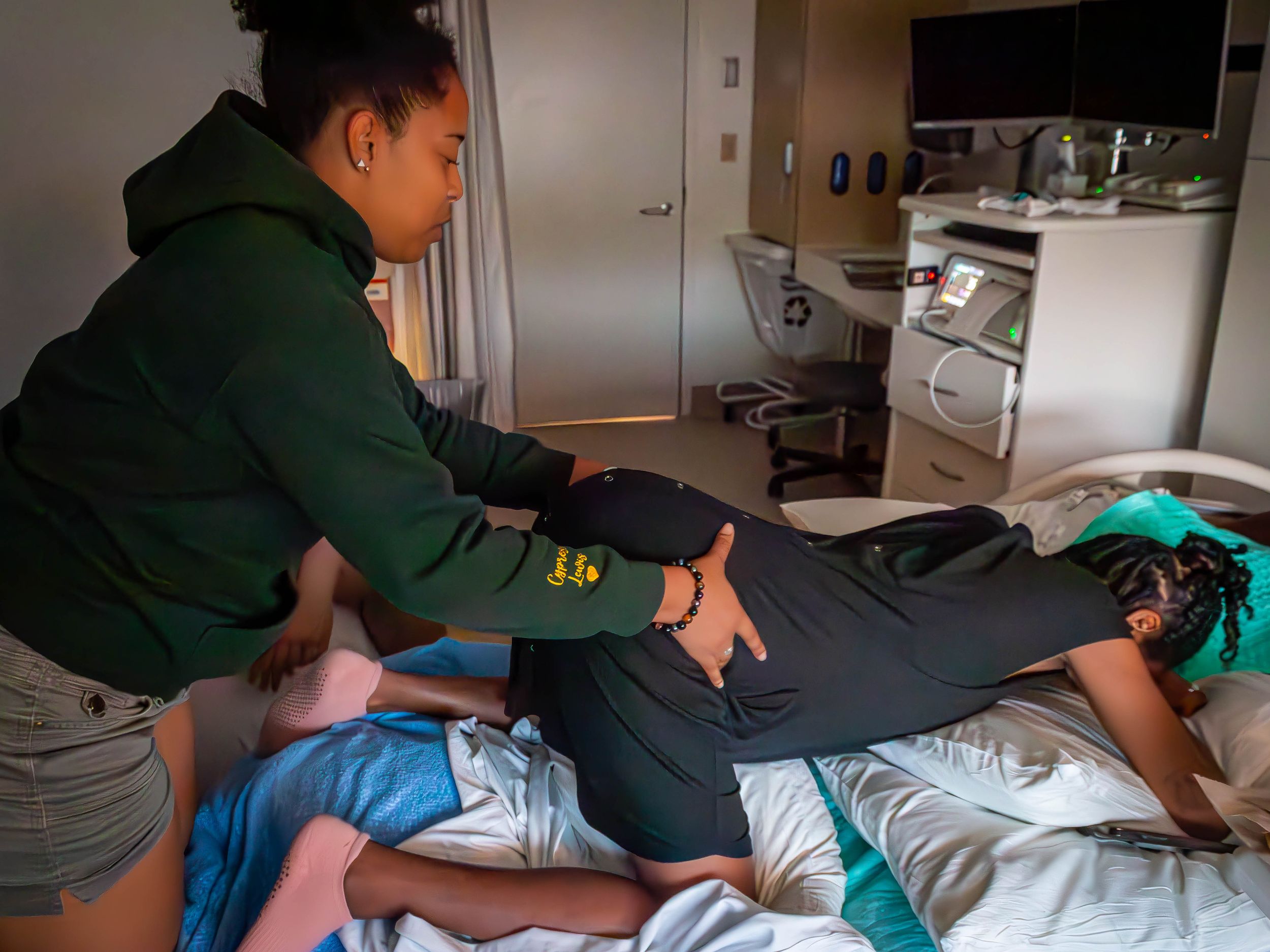 A woman's relative assists her with massage in medical facility during active labor.