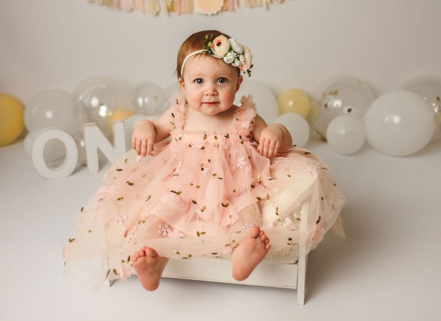 Adorable baby girl in pink tulle dress on vintage prop bed for first birthday photo session at Somerset Portraits in Charlottesville, VA