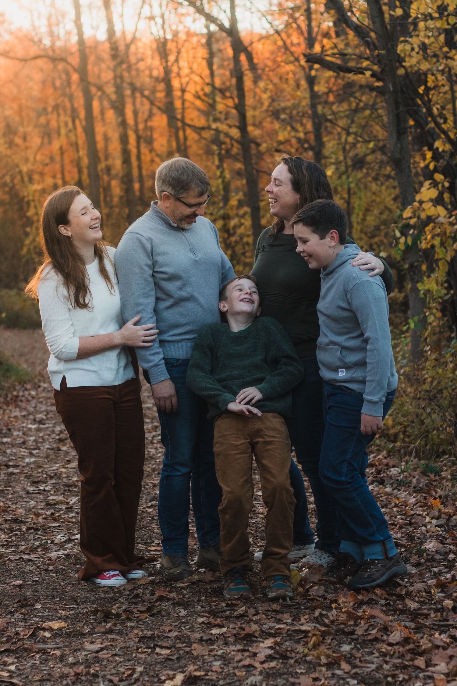 Family laughing and smiling together during golden hour lifestyle family session in Farmington Hills, Michigan.