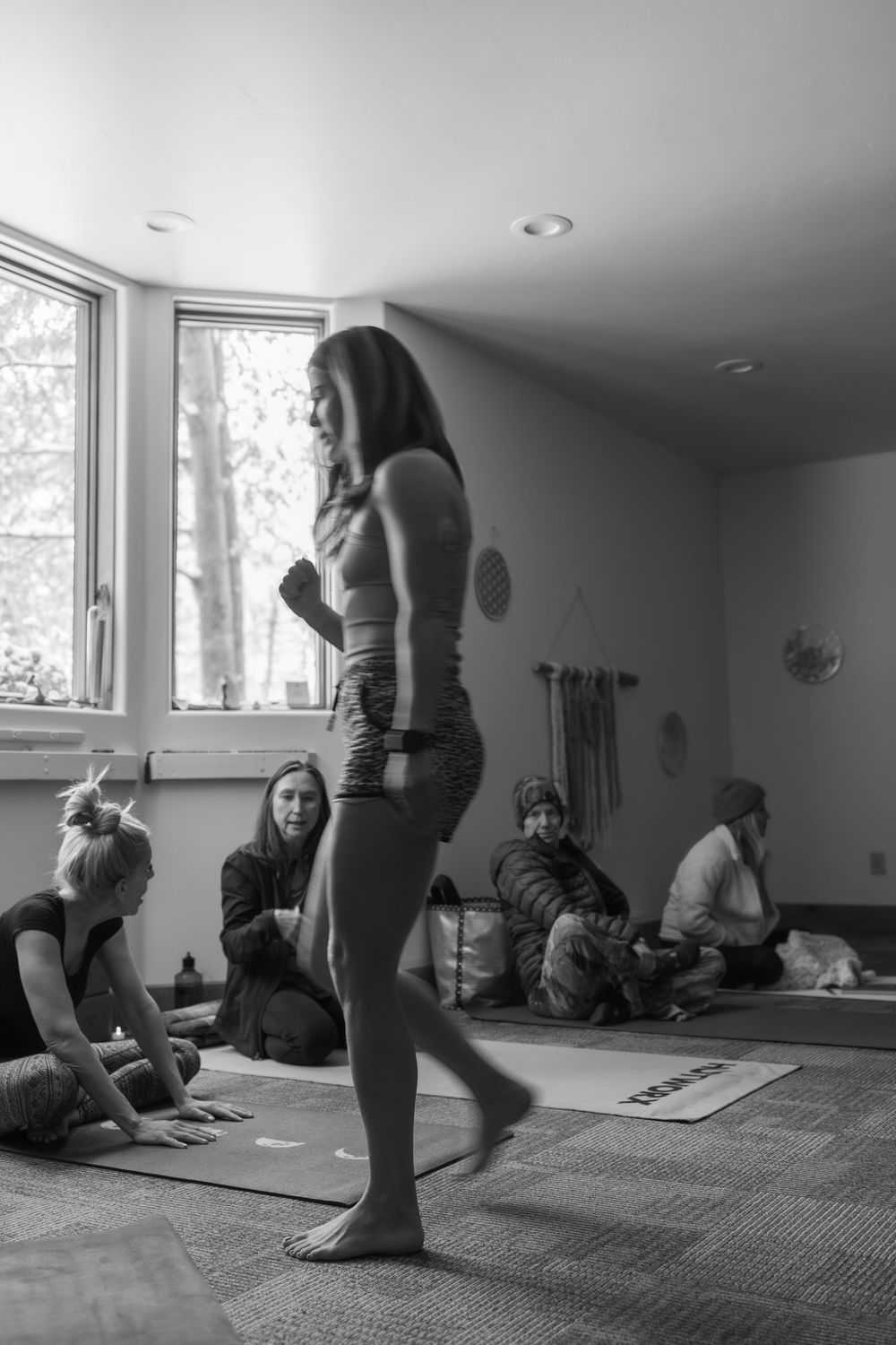 A yoga class practices meditation and stretching exercises on mats in a serene studio space with natural lighting.