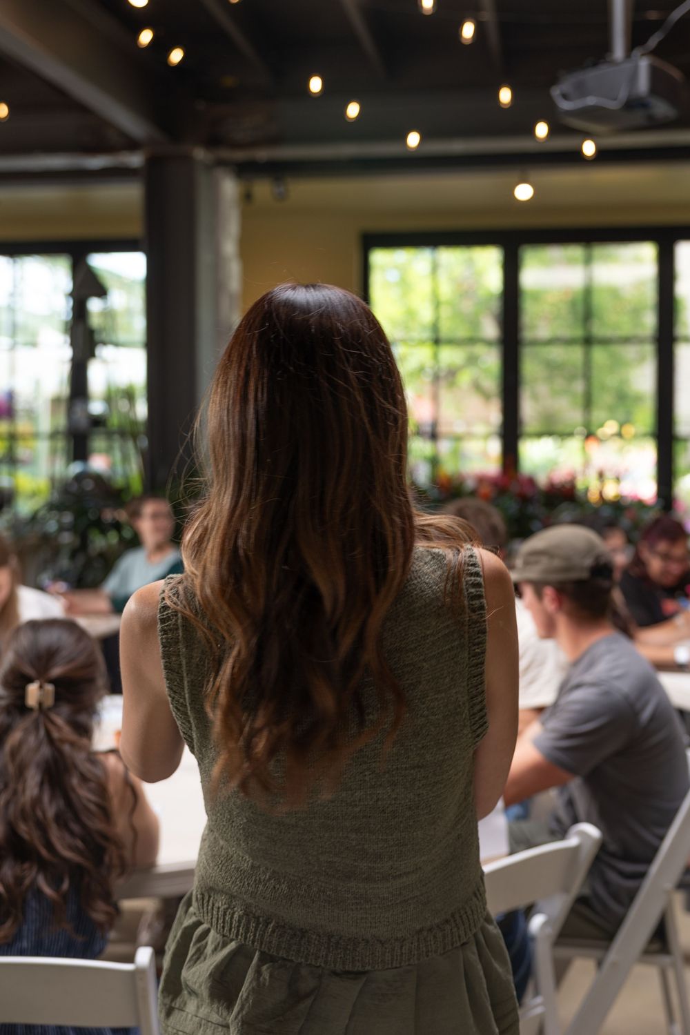 People gathered in an event space with string lights overhead and windows letting in natural light.
