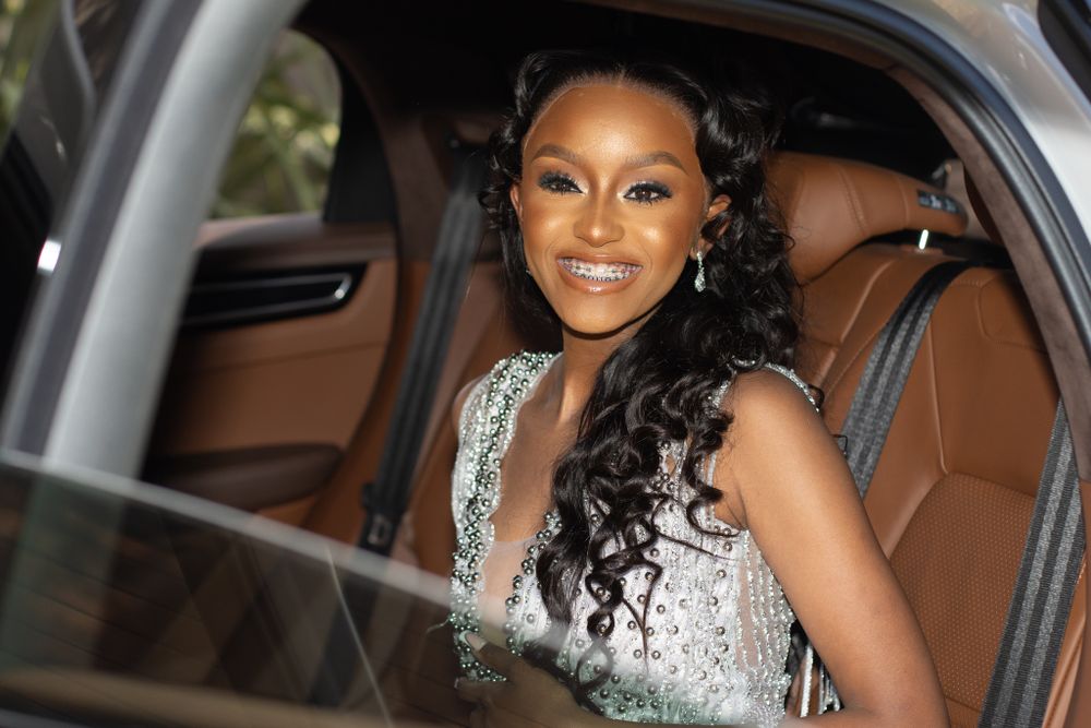An elegant silver sequined gown sparkles inside a luxury vehicle with tan leather interior.